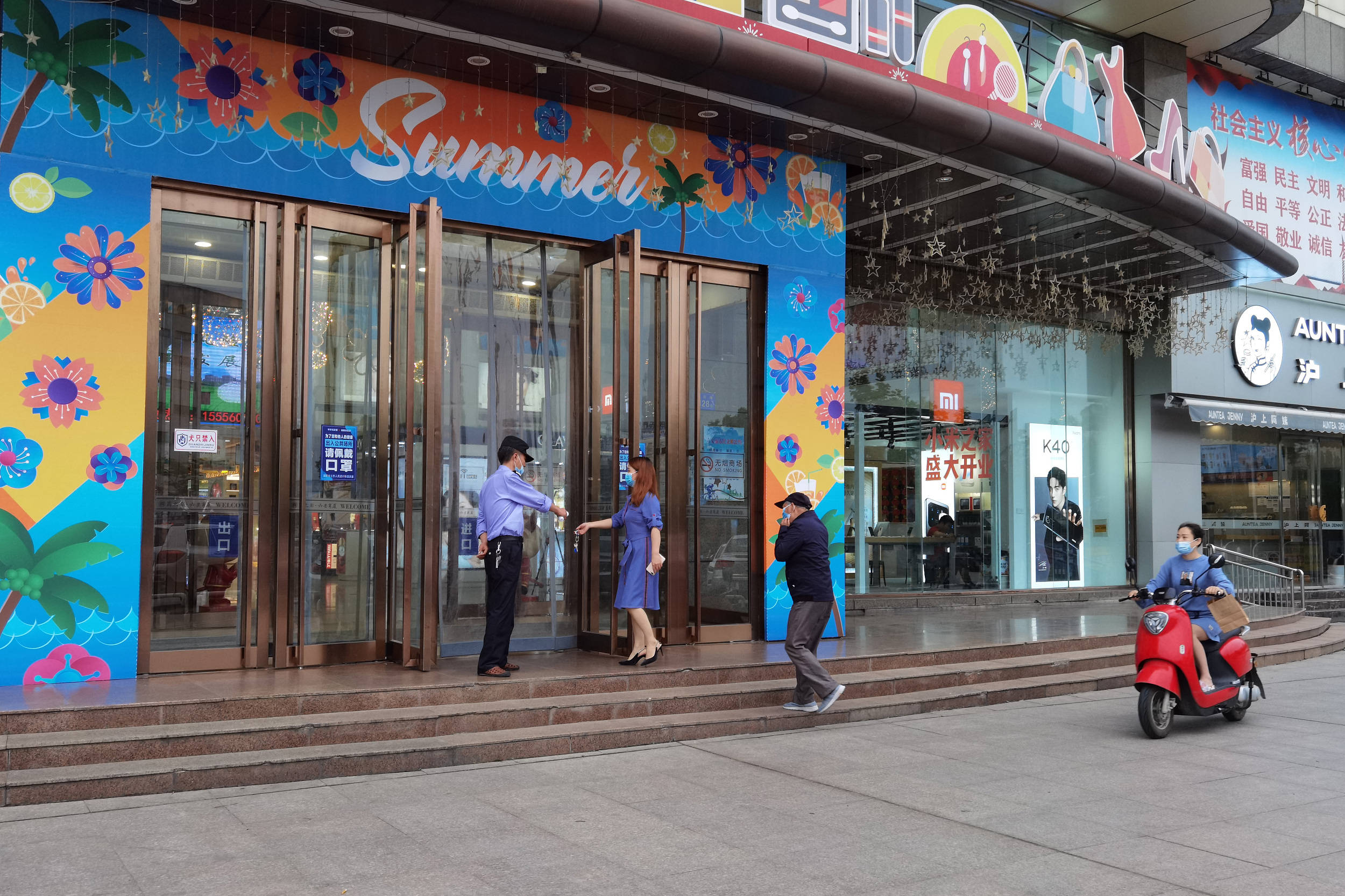 2021年5月13日,安徽六安一家商场门口,工作人员正为进入顾客测量体温.