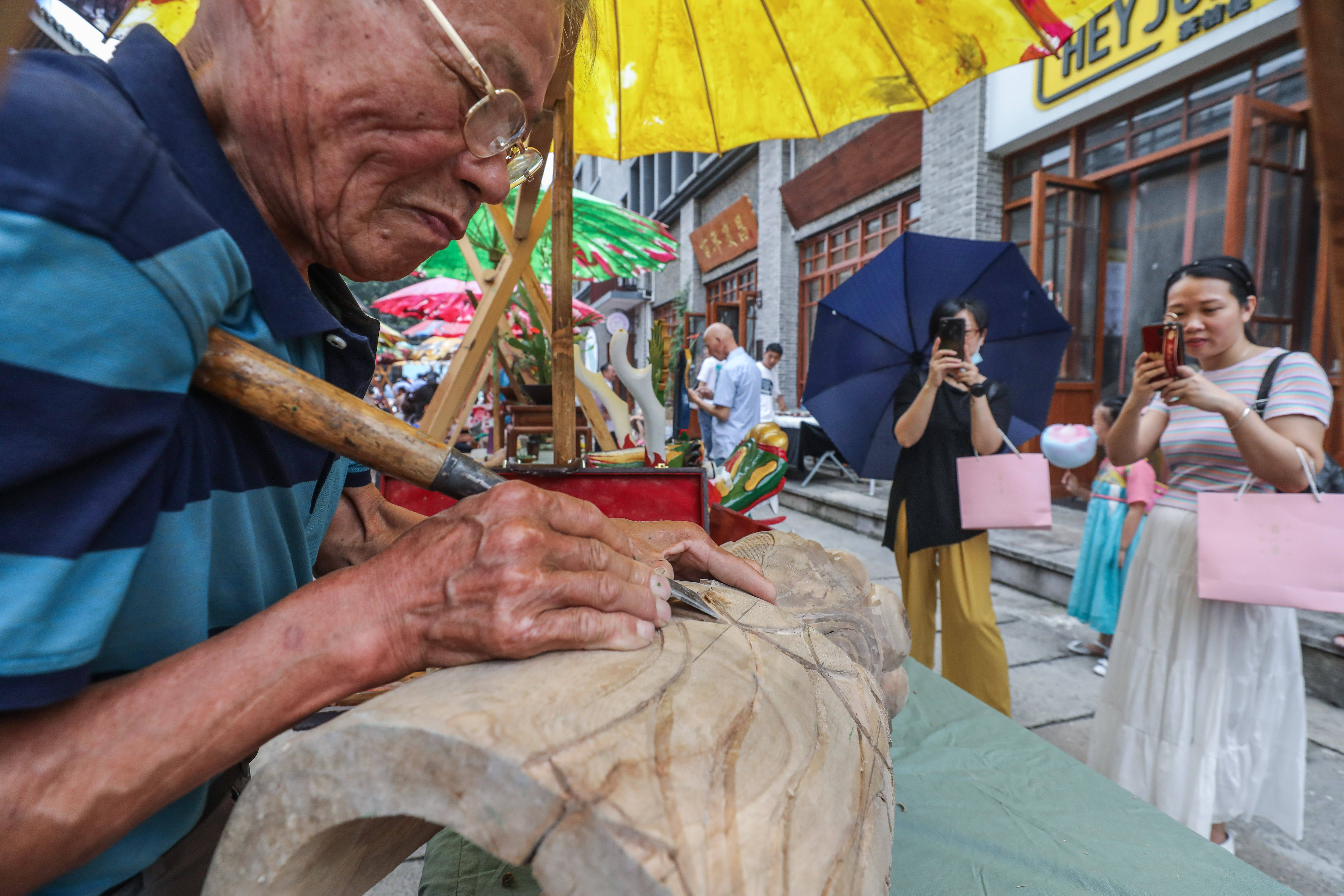 6月12日,手工艺人在瓶窑老街非遗集市上进行木刻技艺展示