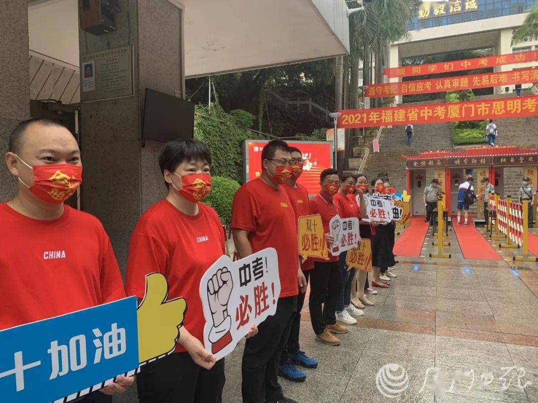 中学考点门前 聚集了20余位身着红色服饰的老师 手持"中考加油"标语