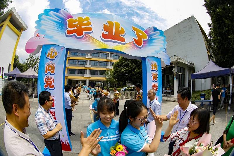 起航"横幅上郑重写下自己的姓名,并依次有序地穿过"毕业门"离开校园