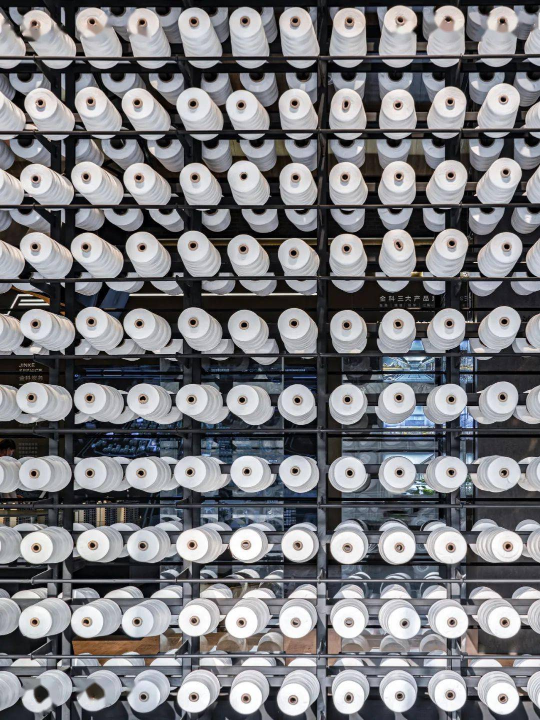 密集的纺织纱锭跳脱出空间又融入整个空间,形成强烈的现代装置艺术的