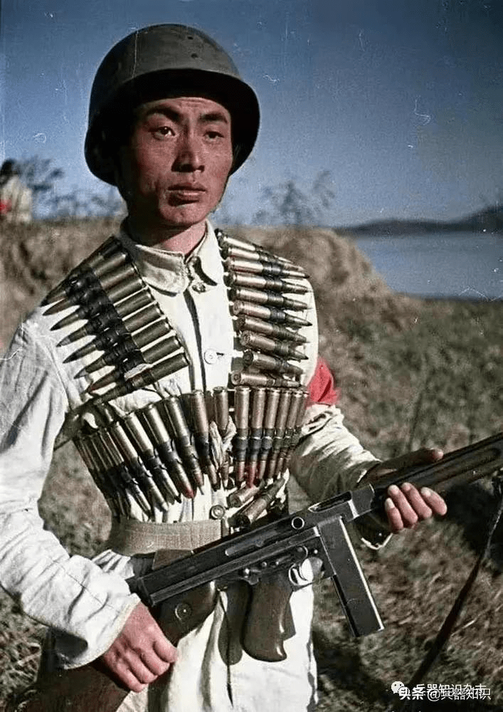 一位头戴美式钢盔,手持汤姆逊m1a1型冲锋枪的解放军战士,身上还挂