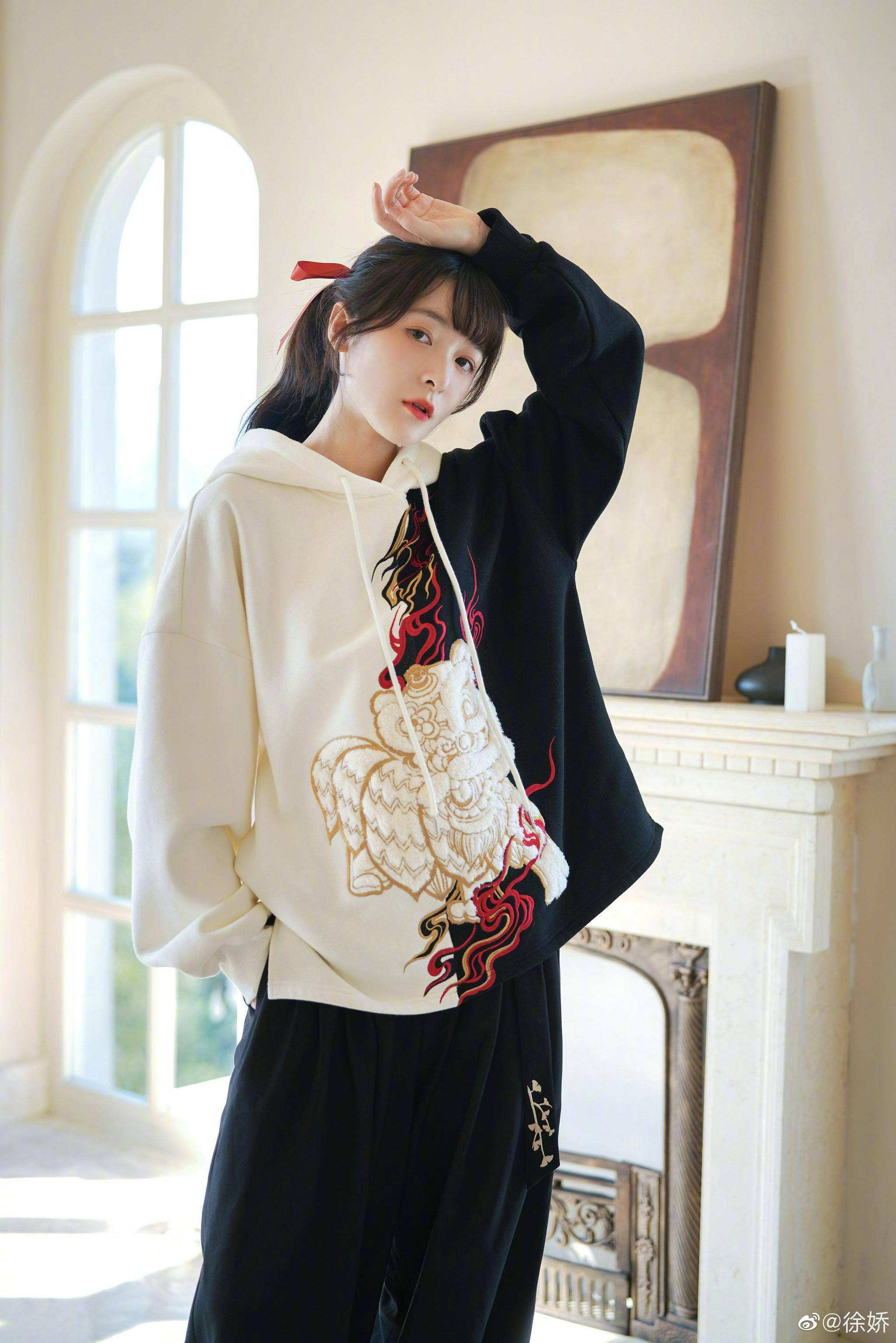 照片中,徐娇身穿黑白拼接卫衣搭配黑色休闲裤,脚踩同色系马丁靴,衣服