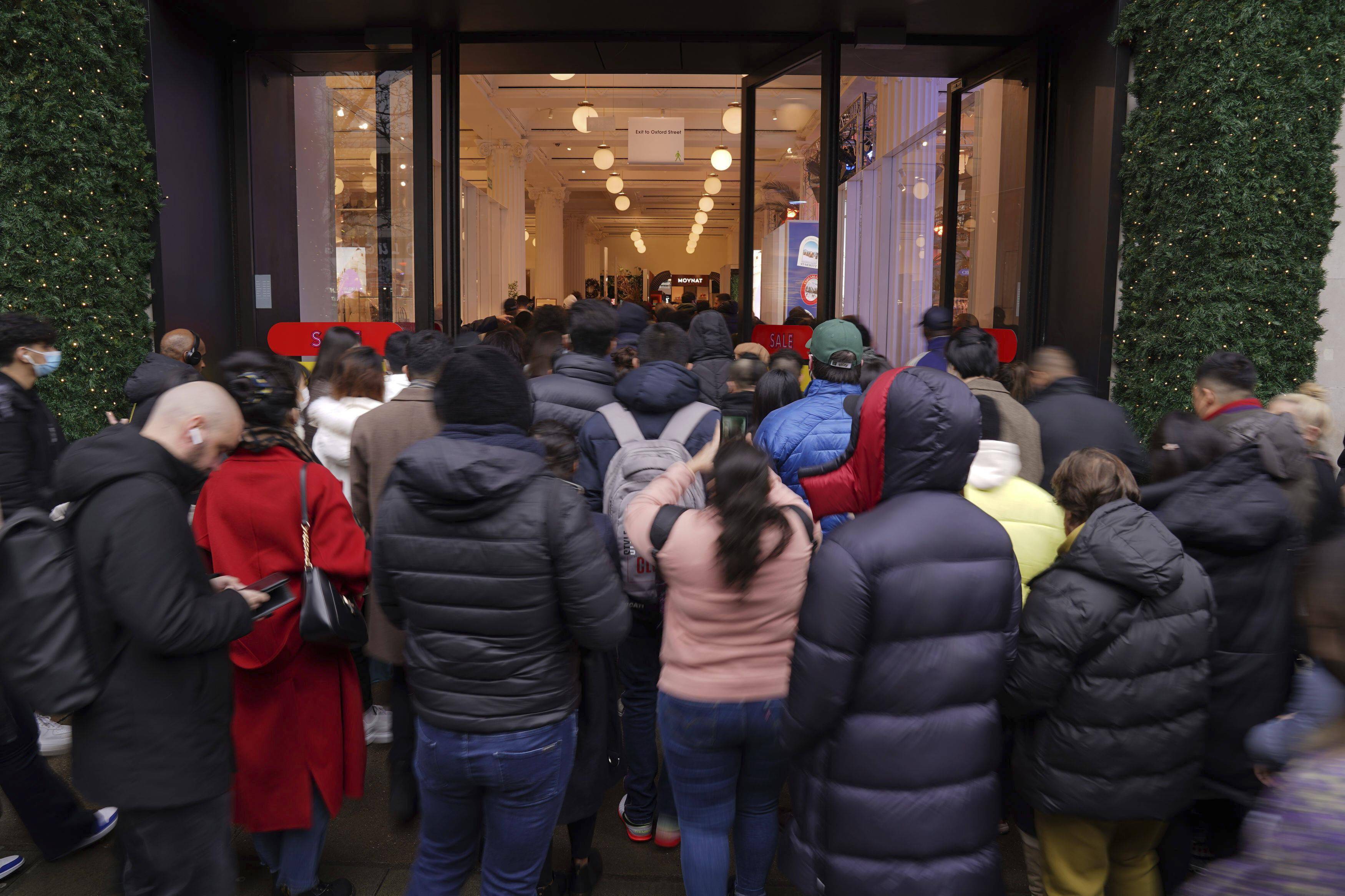 12月26日,工作人员在英国伦敦的哈罗德百货商店外为排队的顾客提供