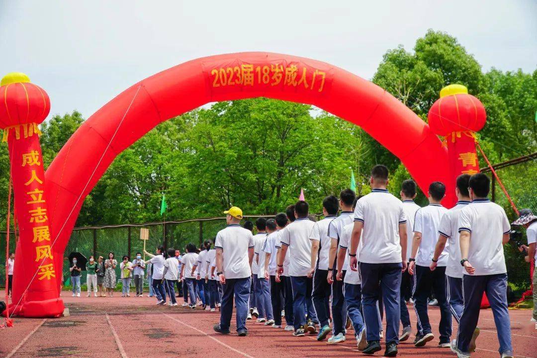 同学们跨过成人门,并共同在2023届十八岁成人仪式横幅上签名留念,用