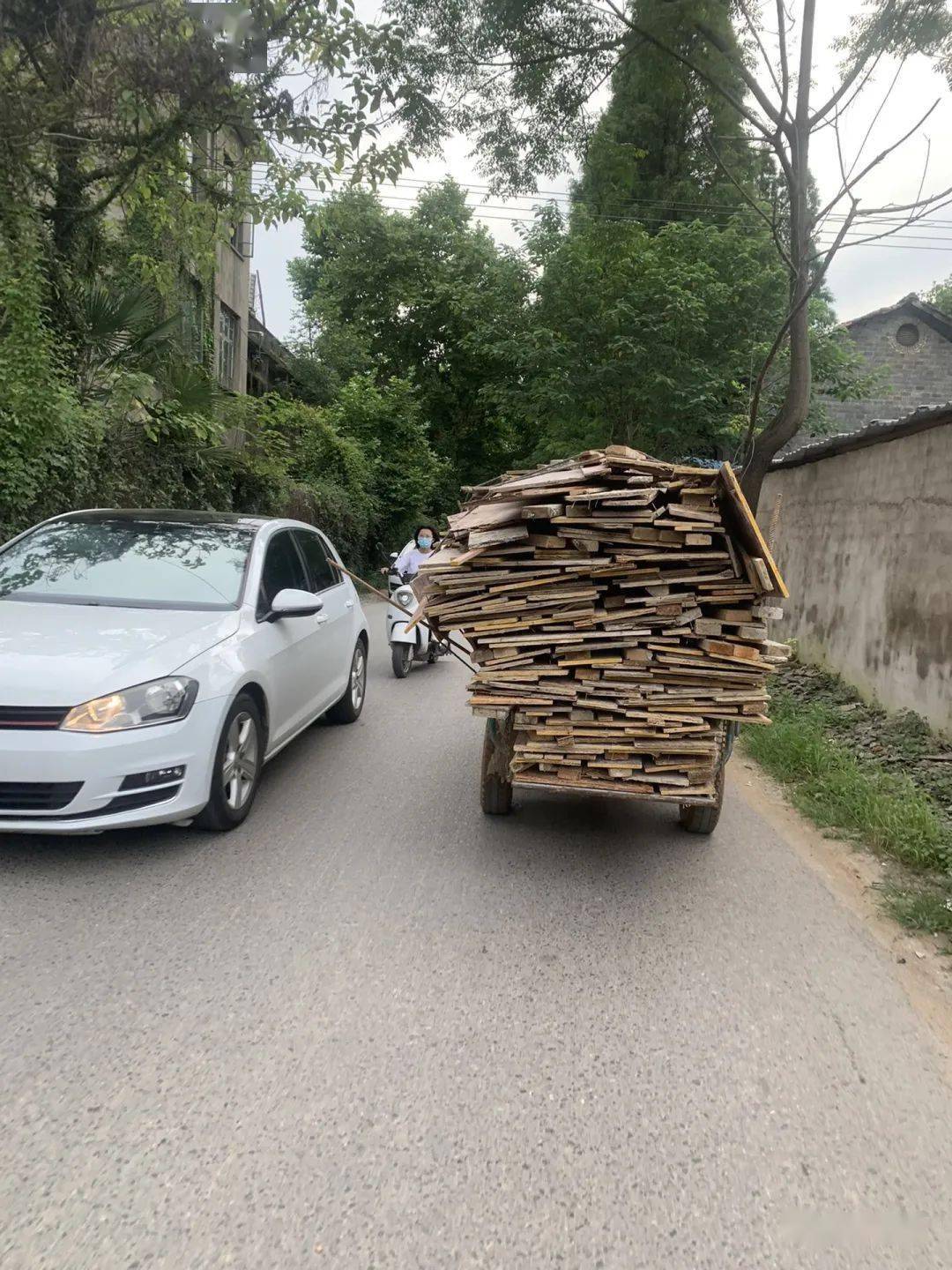 本就是剛好過兩輛車的馬路上,有一個三輪車載著廢舊木板,但由於路上