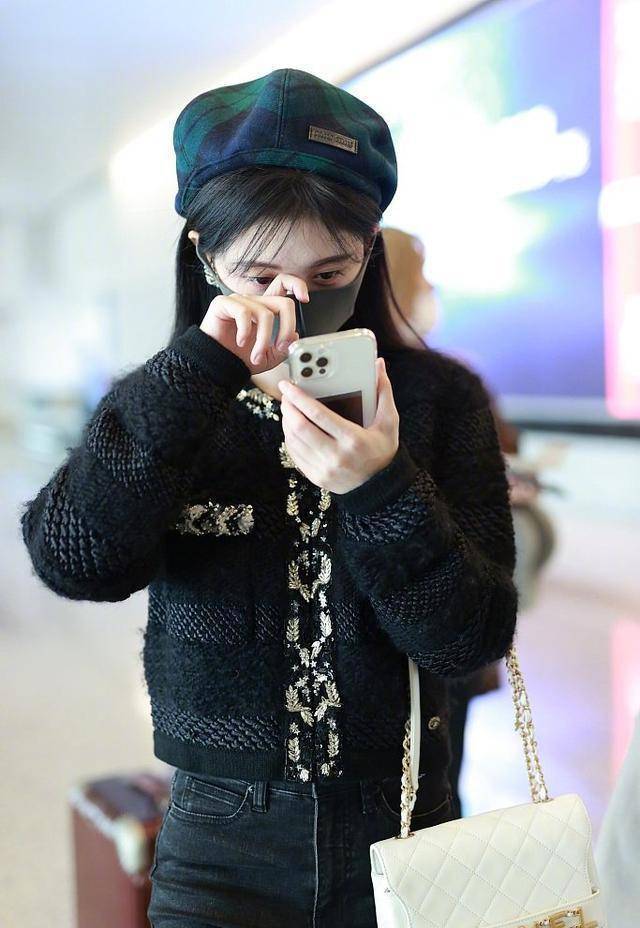 只见鞠婧祎用一件黑色小香风毛衣配黑色牛仔裤和马丁靴,边走边用手机