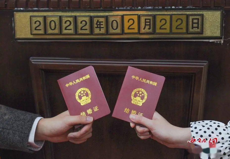 资料图:2022年2月22日,浙江杭州,一对新人拿结婚证和日期数字拍照.