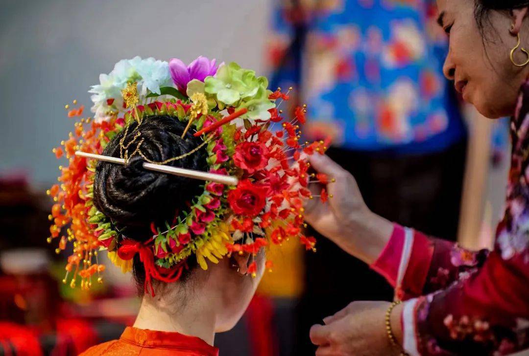 圆髻四周戴上三串花环,有洁白高雅的素馨花,有鹅黄色的含笑花,有球状