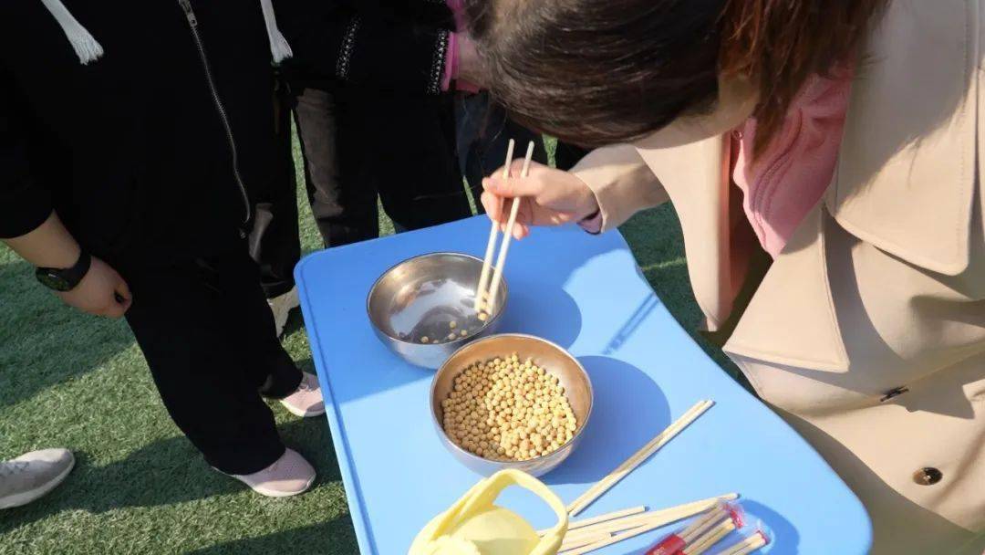 游戏规则:一人从盛有豆子的碗中用筷子夹起,放另一碗中10个豆子,此