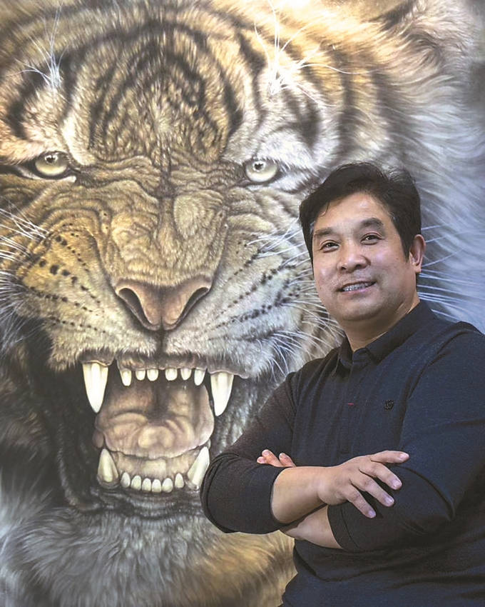 王建民手拿毛笔,蘸上少许墨汁,细心勾勒间,一只猛虎长啸着跃然纸上